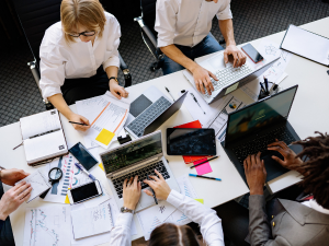 Team collaboration meeting with laptops and documents around conference table