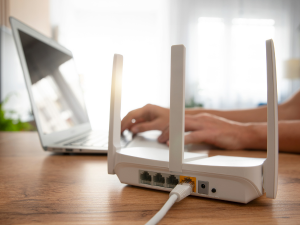 Office Wi Fi router on a desk with a laptop in the background..