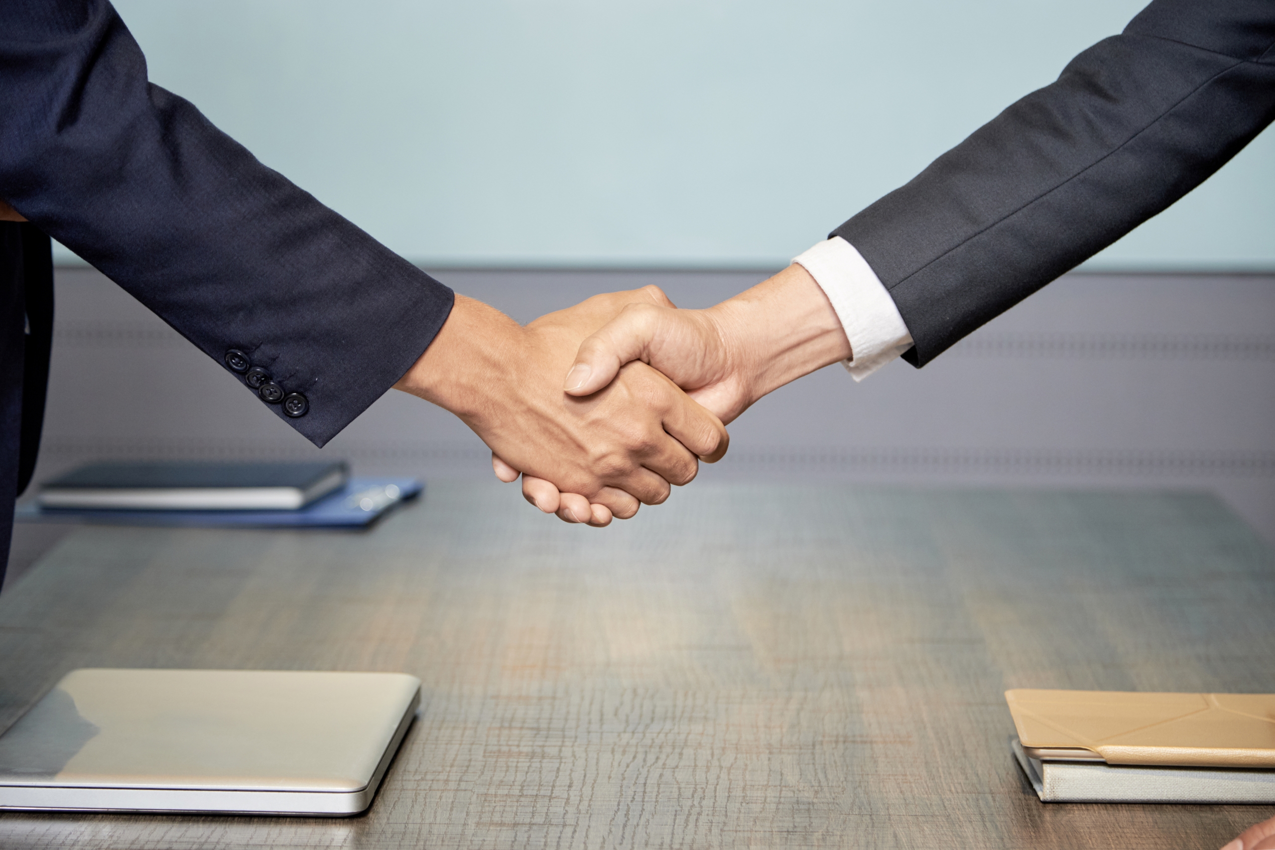 Two business professionals shaking hands over a conference table