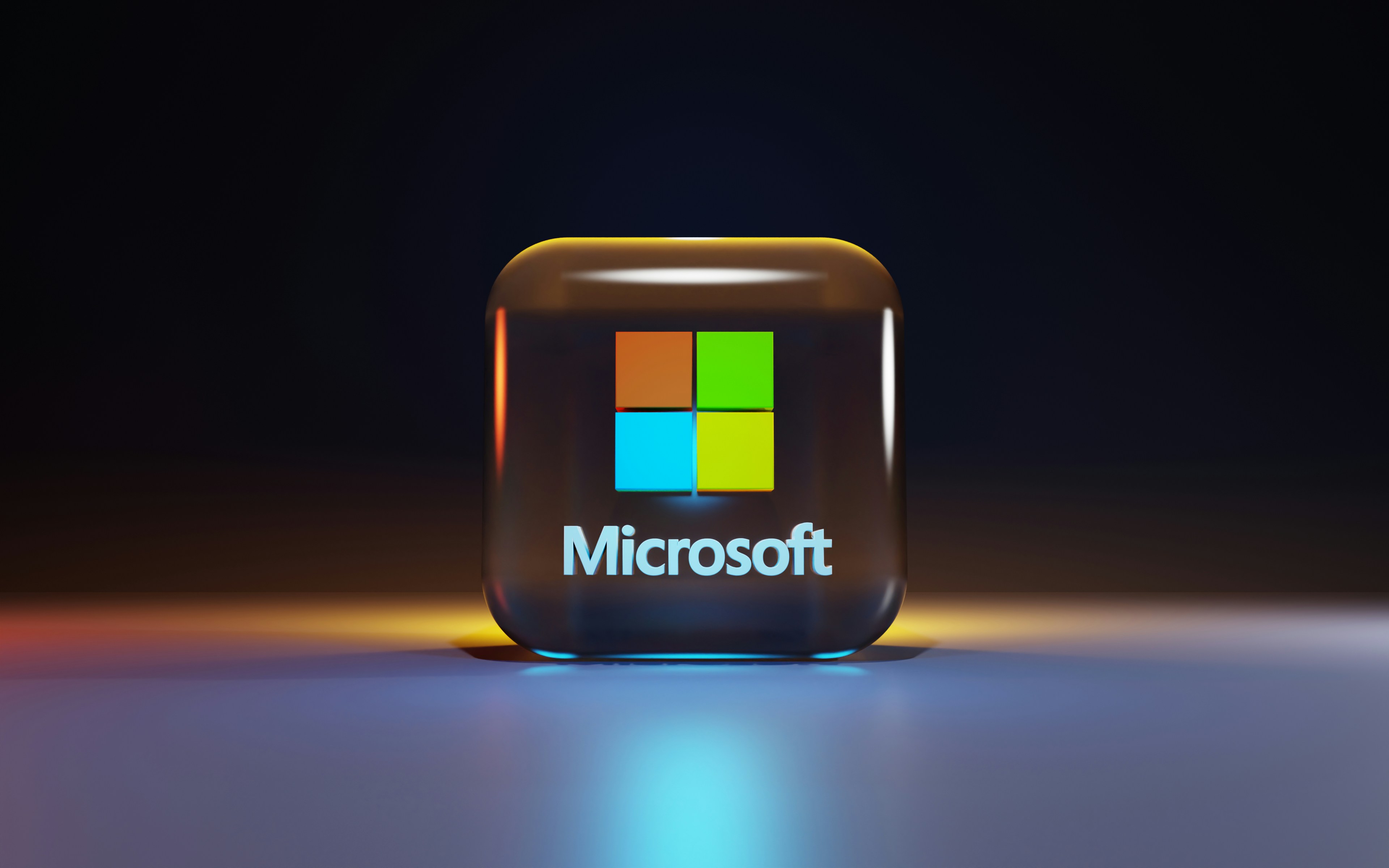 Glowing Microsoft logo on glass cube in dark setting