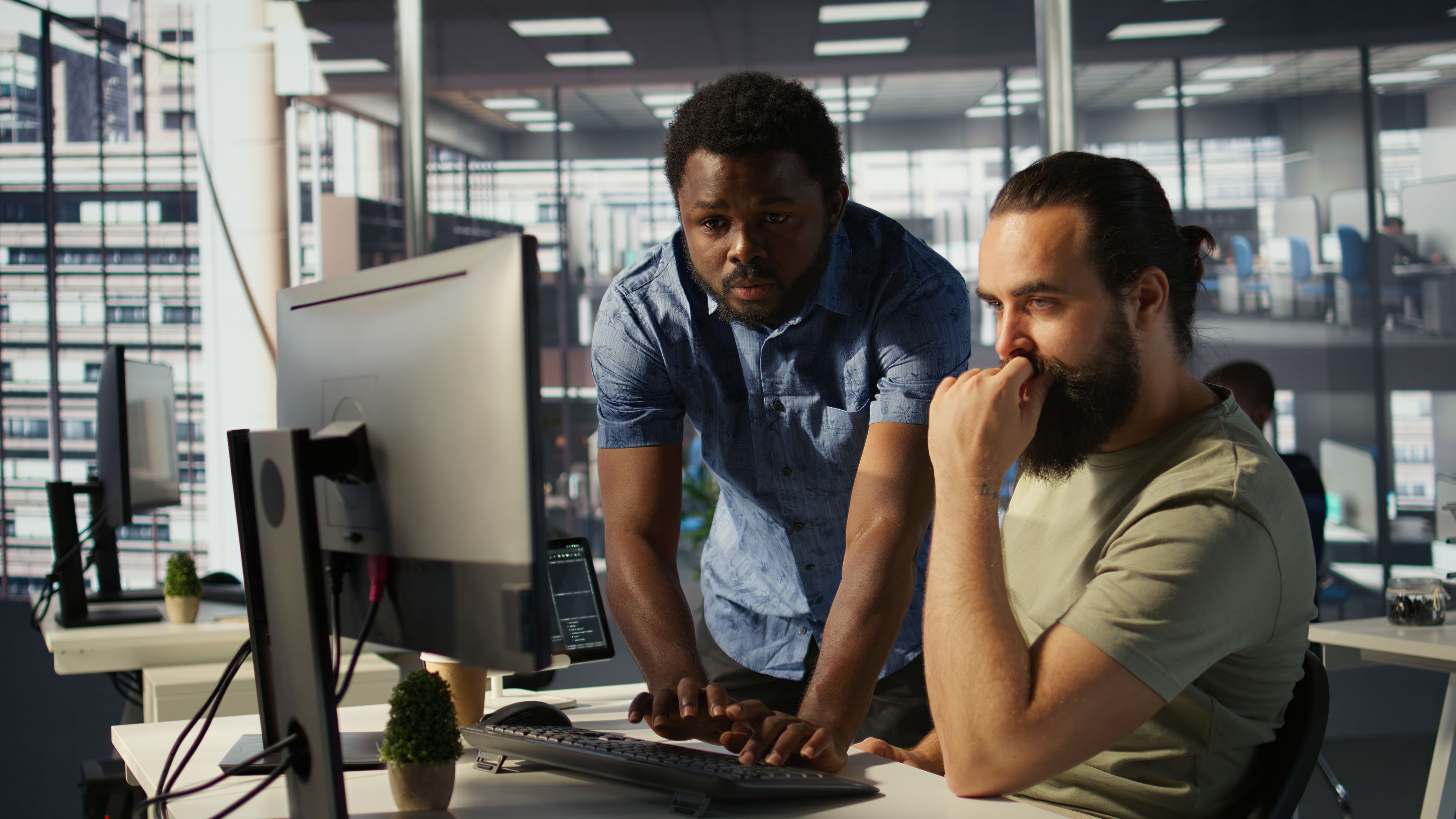 IT specialist helping colleague, typing on desktop's keyboard.